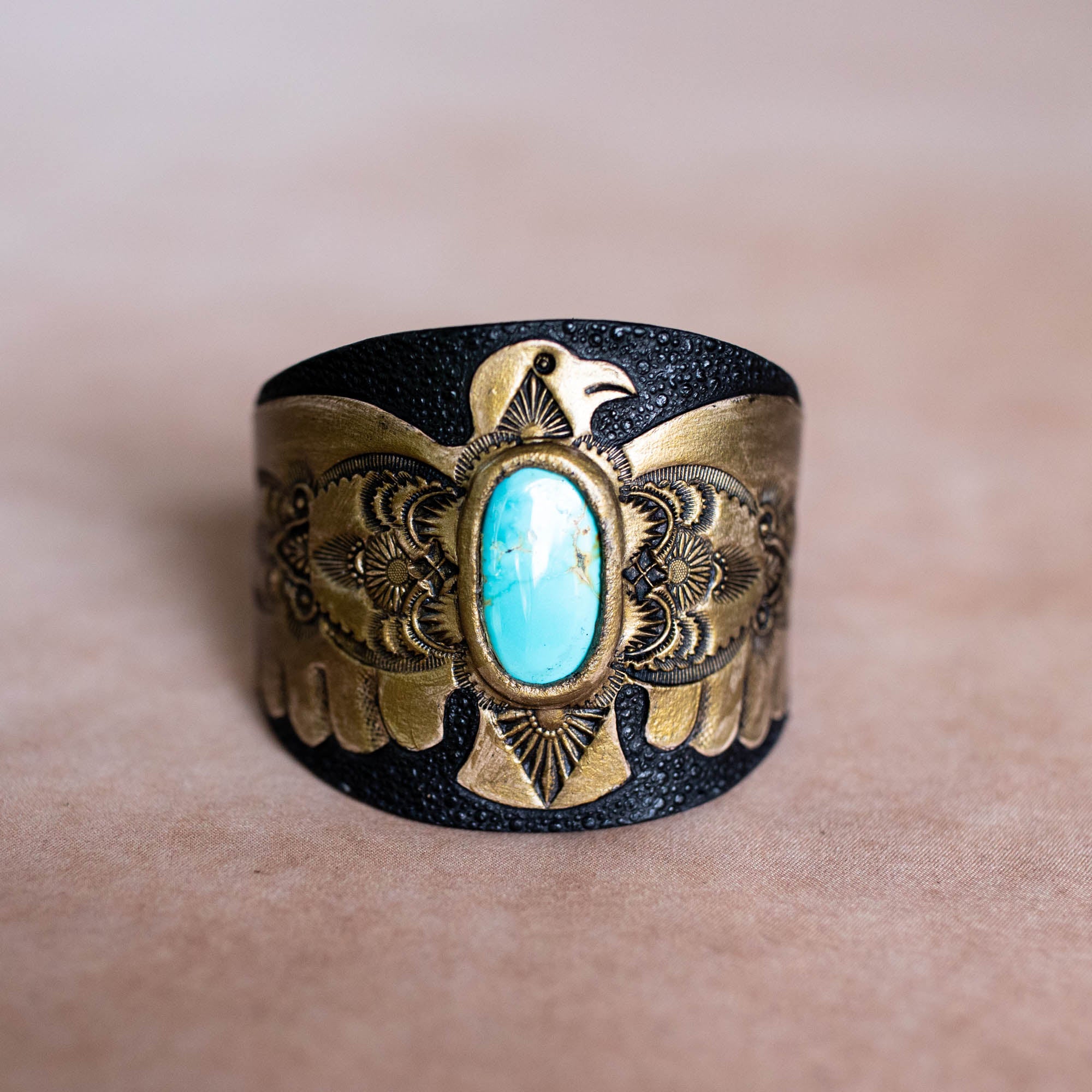 Decorative cuff bracelet with turquoise stone and gold accents on a skin background