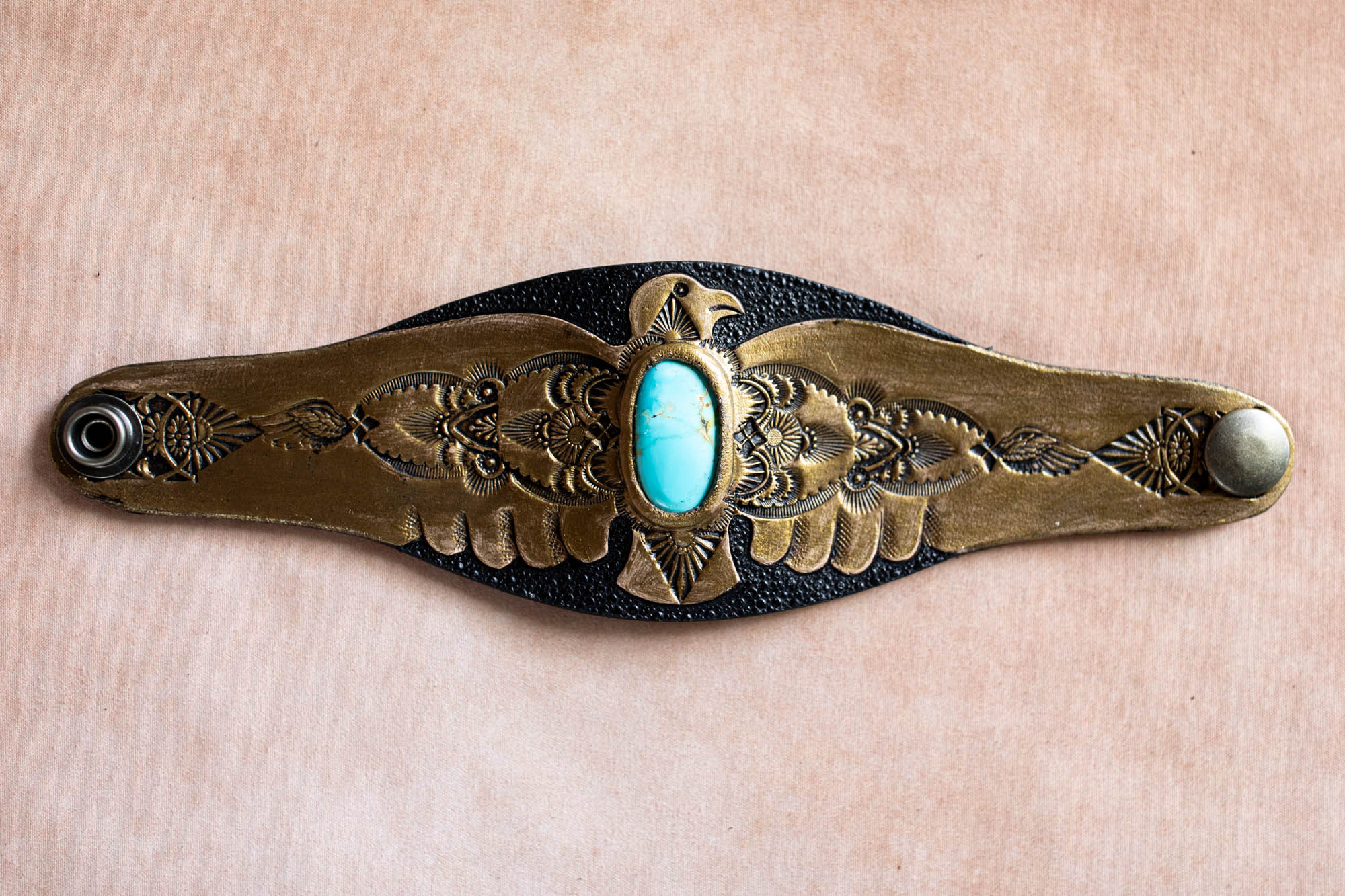 Decorative belt buckle with turquoise stone on a beige background